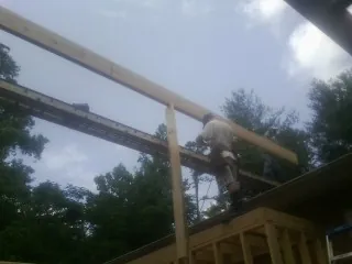 Carpenter setting a ridge beam over a new addition frame — Ice Dam Removal by Roofing Brothers in Leighton