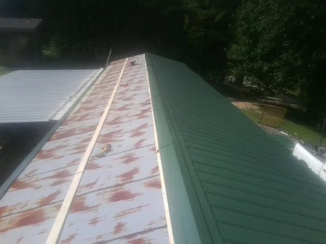 Old rusted panels beside newly installed green metal roofing — Wind Damage Roof Repair by Roofing Brothers in Leighton