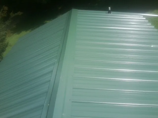 New green metal panels meeting at the ridge of a roof — Flat Roof Repair work by our crew in Leighton