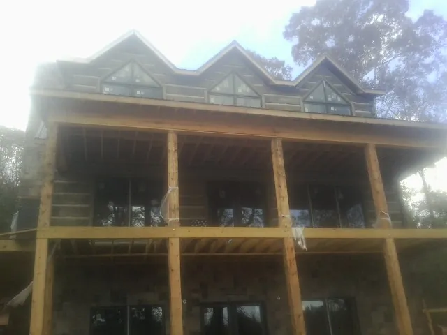 Dormers and porch framing on a large log home under construction — Roof Coating work by our crew in Leighton